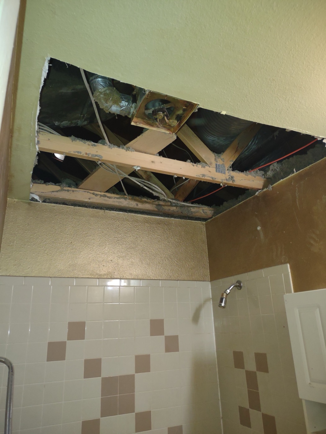Bathroom ceiling opened up — joists, exhaust fan vent and wiring exposed